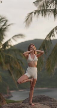 Young Woman Practicing Yoga Tree Pose on Tropical Coastline Rocks