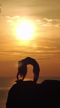 Woman Practicing Yoga Silhouetted Against a Golden Ocean Sunset