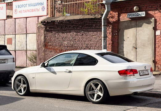 White BMW 3 Series E92 luxury sport coupe car parked outdoors on an asphalt road. Premium German RWD or xDrive sports automobile engineered on an E90 platform chassis with an elegant body silhouette.