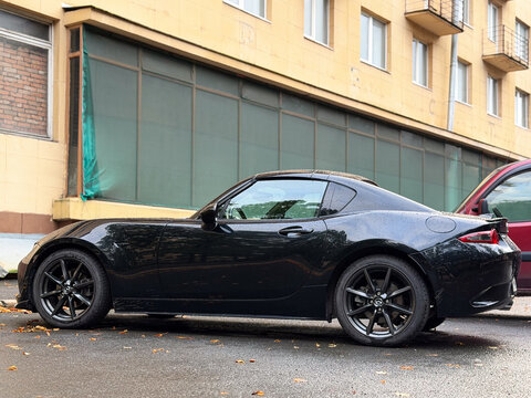 Black Mazda MX-5 Miata RF ND luxury compact roadster model car parked outdoors. Premium Japanese rear-wheel drive RWD sports automobile with stylish aerodynamic convertible targa body profile design. 