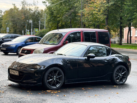 Black Mazda MX-5 Miata RF ND luxury compact roadster model car parked outdoors. Premium Japanese rear-wheel drive RWD sports automobile with stylish aerodynamic convertible targa body profile design. 