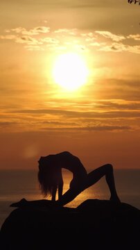 Woman Performing Yoga Silhouette Against Golden Ocean Sunset