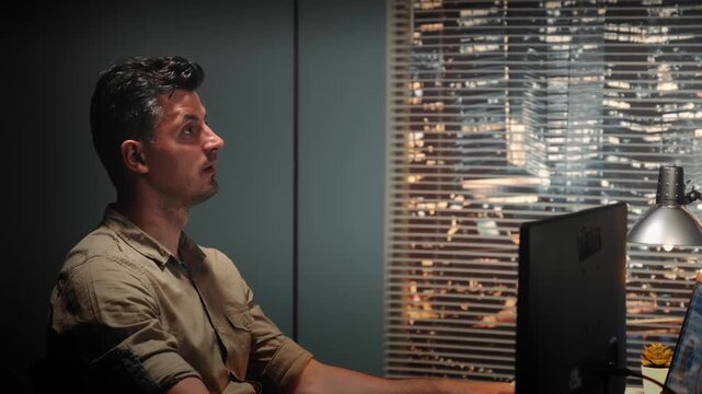 A middle-aged engineer discusses 3D component design using computer-aided design in a stylish office with city lights visible through large blinds at nighttime.