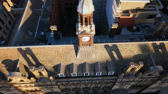 Aerial video looking down at the historic Old Post Office building, clock tower, and outdoor terrace overlooking Leeds City Square in early morning sun.