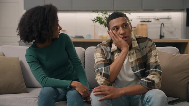 Irritated African American parents naughty little boy child running in living room annoyed mother father holding head stressed family bad behavior woman mom dad man son kid difficult parenting indoor