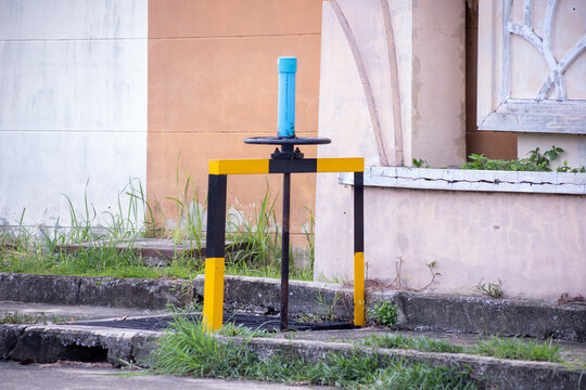 Yellow and black safety-painted manual sluice gate water control valve mounted on concrete drainage cover in urban infrastructure