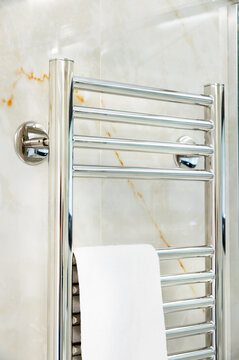 Chrome heated towel rail mounted on marble tile wall