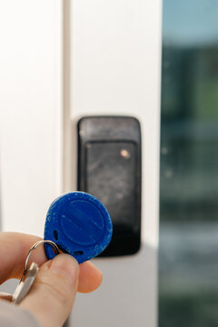 A person uses an RFID key fob to access a secure door via an electronic card reader, symbolizing modern security technology.