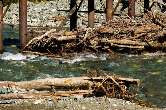 Debris Jamming Underneath Wooden Bridge Over Flowing River