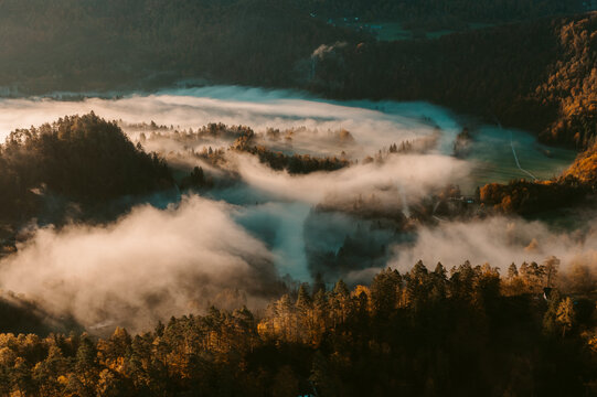Aerial view of a foggy autumn valley nestled between mountains in the Slovenian countryside