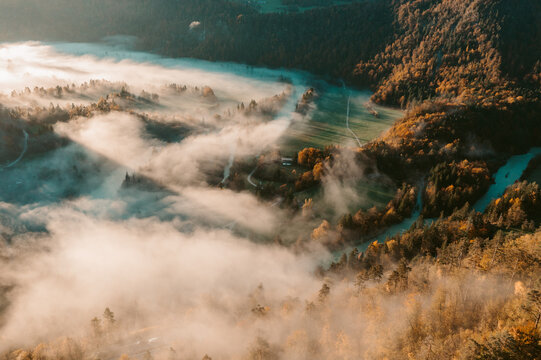 Aerial view of a foggy autumn valley nestled between mountains in the Slovenian countryside