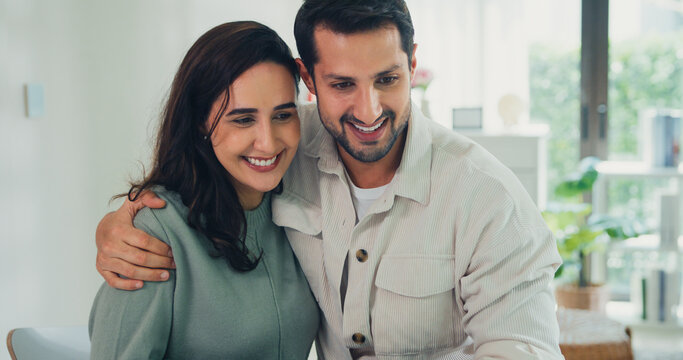 Young Latin couple male, female customers paying by credit card online and laptop shopping online furniture decorate home in living room at home. Young married moving home shopper online concept.