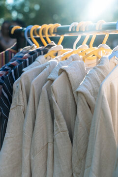 Clothing rack with hanging beige shirts and striped garments