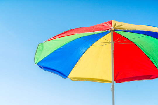 Colorful beach umbrella against a clear blue sky background