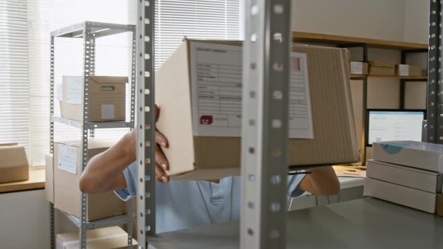 Hispanic young woman carrying cardboard parcel box and placing it on storage rack. Footage ideal for e-commerce logistics, delivery services, online store inventory management projects