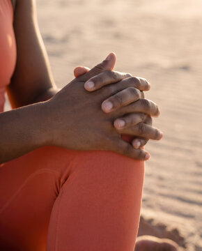 Close detail of clasped hands resting on knees in a contemplative pause
