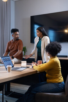 African American team meeting in office, standing woman gesturing in casual attire with laptop
