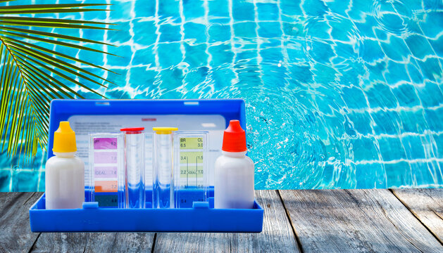 Water tester test kit over crystal clear swimming pool water background, outdoor day light