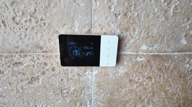 Hand activating a digital heating boiler controller to regulate temperature and manage home energy consumption efficiently, illustrating smart home climate control and domestic heating management.