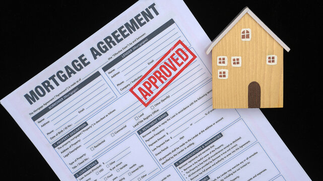Approved mortgage agreement document gives successful relief and confidence during complete housing loan process beside house model