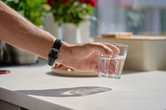 Person taking glass of water from kitchen counter