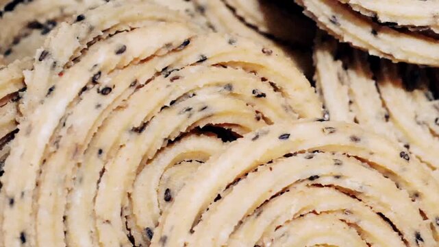 Extreme macro close up of raw spiral chakli murukku dough with black sesame seeds.