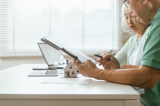 senior couple and documents with laptop for finance, budget planning or retirement annuity on sofa. Elderly man, woman or house with smile, computer or paperwork for pension fund or insurance