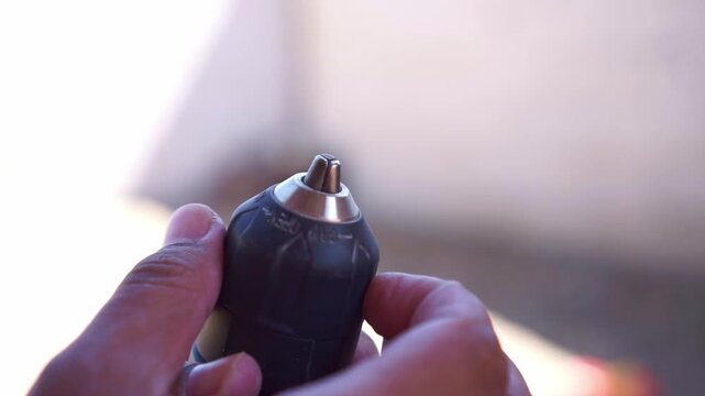 hands adjusting a drill chuck to loosen the bit holder. Tool footage showing DIY repair, construction work, and handyman activity.