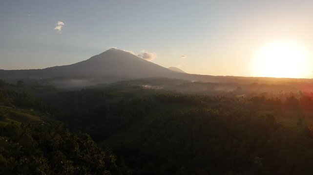 Drone flying upwards and sideways over ricefields at sunrise with vulcano in the background in 4k