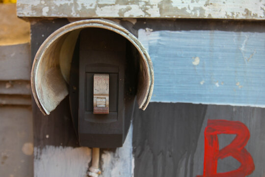 A light switch in the "off" position, mounted on an old wall with a protective cover.
