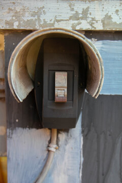 A light switch in the "off" position, mounted on an old wall with a protective cover.