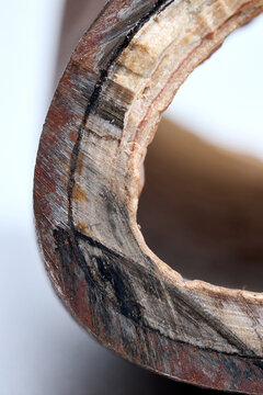 Section of industrial hot water boiler pipe with limescale deposits inside wall, reducing heat transfer efficiency, causing energy loss, corrosion, plumbing blockage, equipment failure