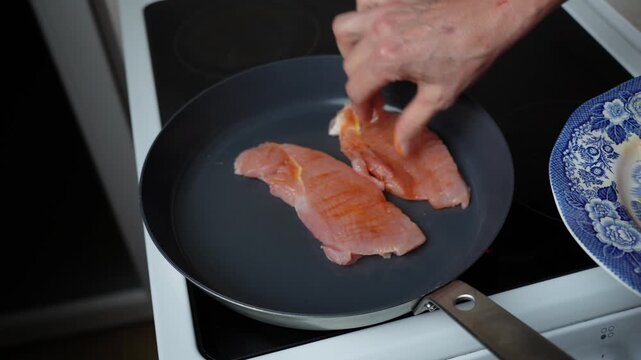 Placing Turkey Steaks Into a Hot Frying Pan. Seasoned turkey steaks are carefully placed into a hot frying pan to begin cooking.