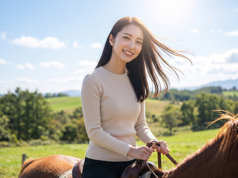牧草地で馬に乗り爽やかな笑顔を見せる女性