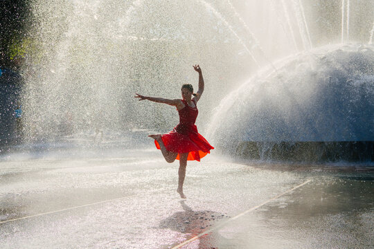 White woman dancing in water spray from fountain outdoors