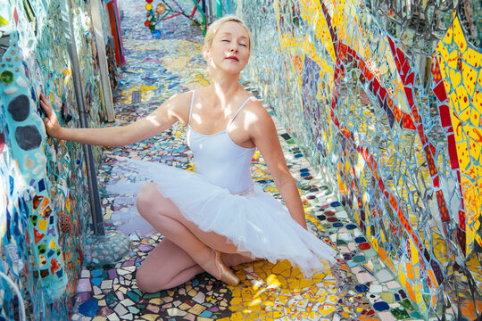 Ballet white dancer kneeling on colorful mosaic art installation