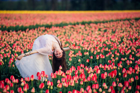 White woman dancing in vibrant red tulip field outdoors in spring