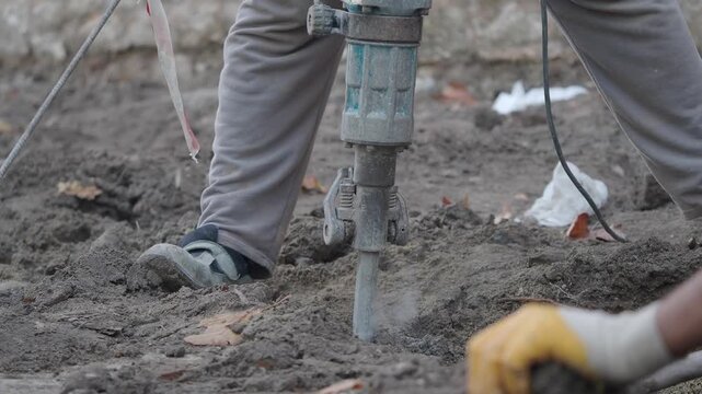 Construction worker using jackhammer to break up ground for new project