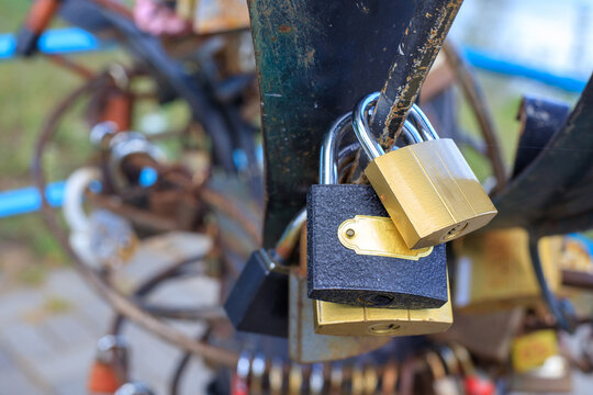 Metal love locks attached to the bridge railing. Brass and iron padlocks fastened by newlyweds in the open air.