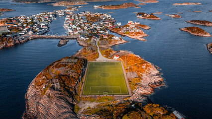 Aerial drone view of the famous Henningsvaer football field and fishing village on rocky islands surrounded by ocean water in Lofoten Norway © Quality by Simon