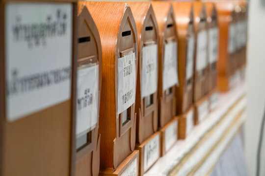 Wooden temple donation boxes line up in a row, each labeled in Thai. The text reads Ruam Pid Thong Phra, meaning Join in Gilding the Buddha.