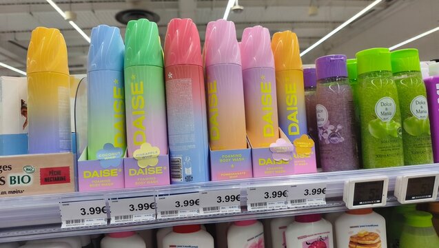 Royan, France - July 25, 2026: E.Leclerc ROYAN CEDEX. Colorful DAISE hair care spray bottles arranged on a supermarket shelf with various price tags visible in a retail environment