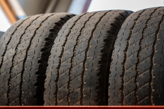 Close-up of worn summer car tires stored on a rack, showing used tread patterns and rubber wear, ideal for tire service, vehicle maintenance, road safety and seasonal storage concepts.
