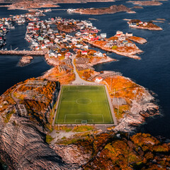 Aerial drone view of the famous Henningsvaer football field and fishing village on rocky islands surrounded by ocean water in Lofoten Norway © Quality by Simon