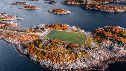 Aerial drone view of the famous Henningsvaer football field and fishing village on rocky islands surrounded by ocean water in Lofoten Norway © Quality by Simon