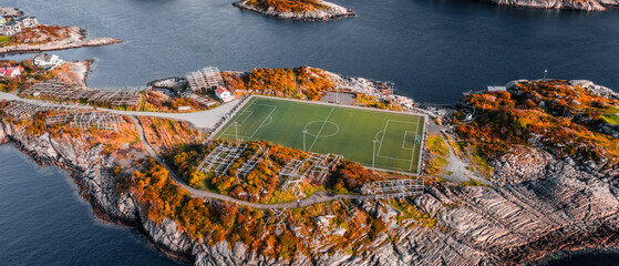 Aerial drone view of the famous Henningsvaer football field and fishing village on rocky islands surrounded by ocean water in Lofoten Norway © Quality by Simon