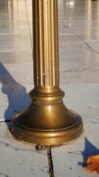 Vertical video: Panning camera from close revealing brass base in plaza to show metal loop and leaf