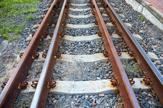 Rusty double gauge railway tracks in Belarus showing dual track system with concrete sleepers and gravel ballast, reflecting transport stagnation, trade disruption and logistics impact.