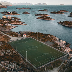 Vertical aerial drone view of the iconic Henningsvaer football field on a rocky island with scenic fjord and mountains in Lofoten Norway © Quality by Simon