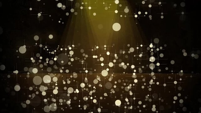 Golden shimmering particles floating in soft yellow spotlight during celebration with bokeh effect